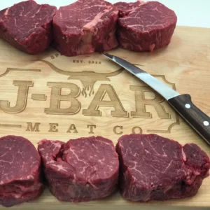 A cutting board with several raw beef and a knife.