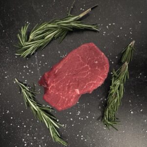A piece of meat and some herbs on the table