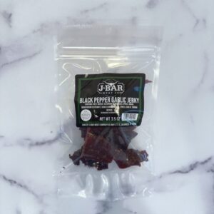 A bag of black pepper chili candy on top of a marble surface.
