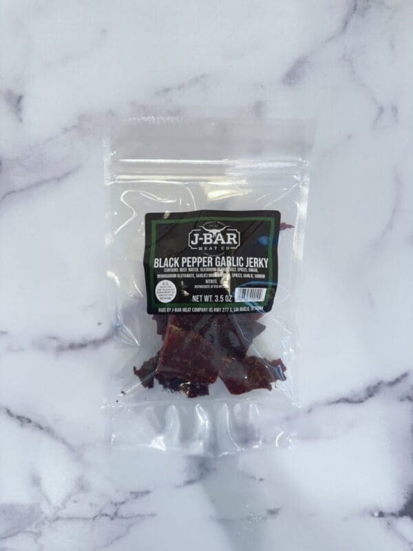 A bag of black pepper chili candy on top of a marble surface.