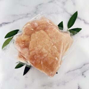 A piece of meat in plastic bag on top of marble table.