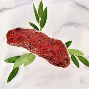 A piece of meat with leaves on the side.