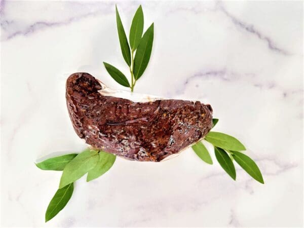 A piece of meat with leaves on the side.