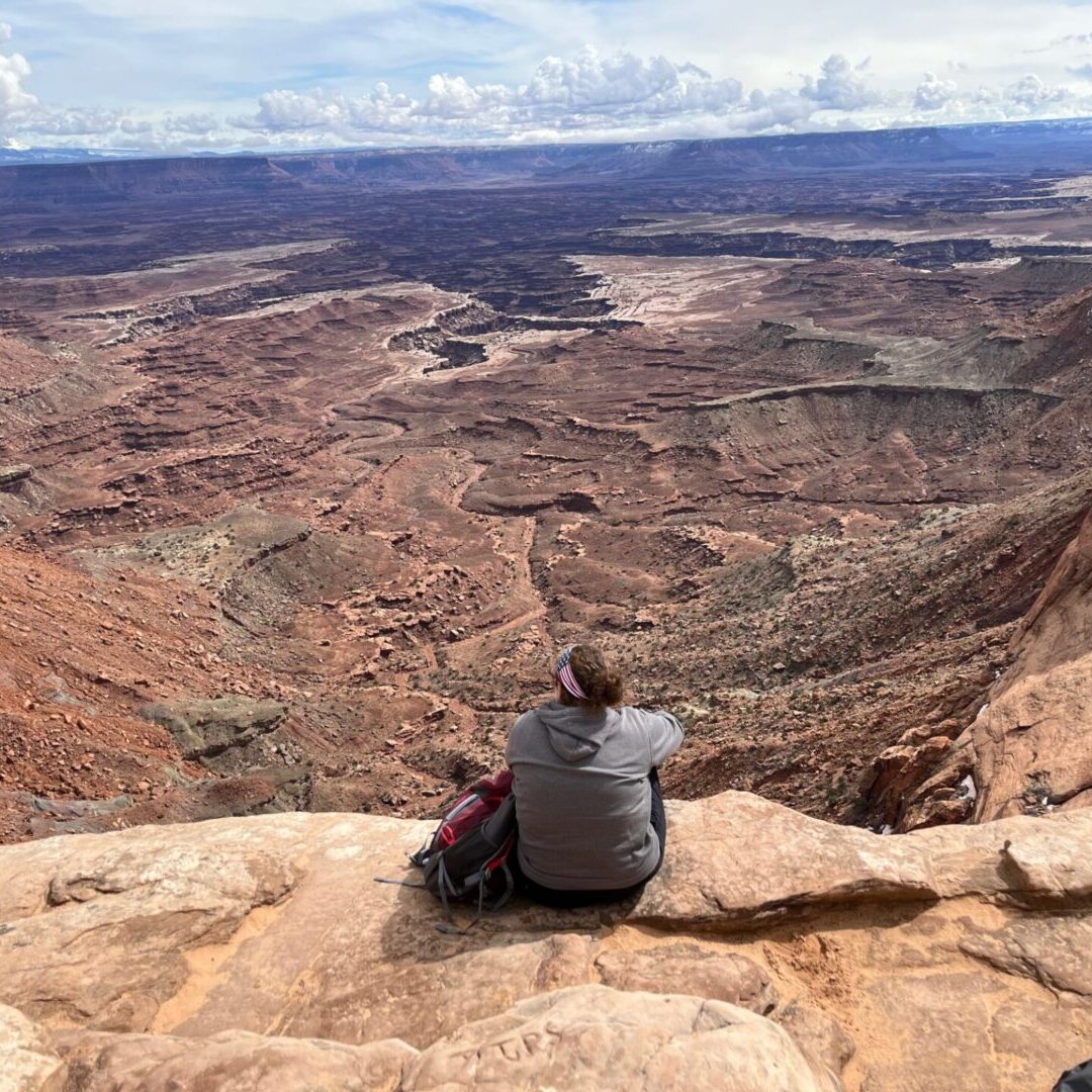 A person sitting on top of a mountain looking at the view.